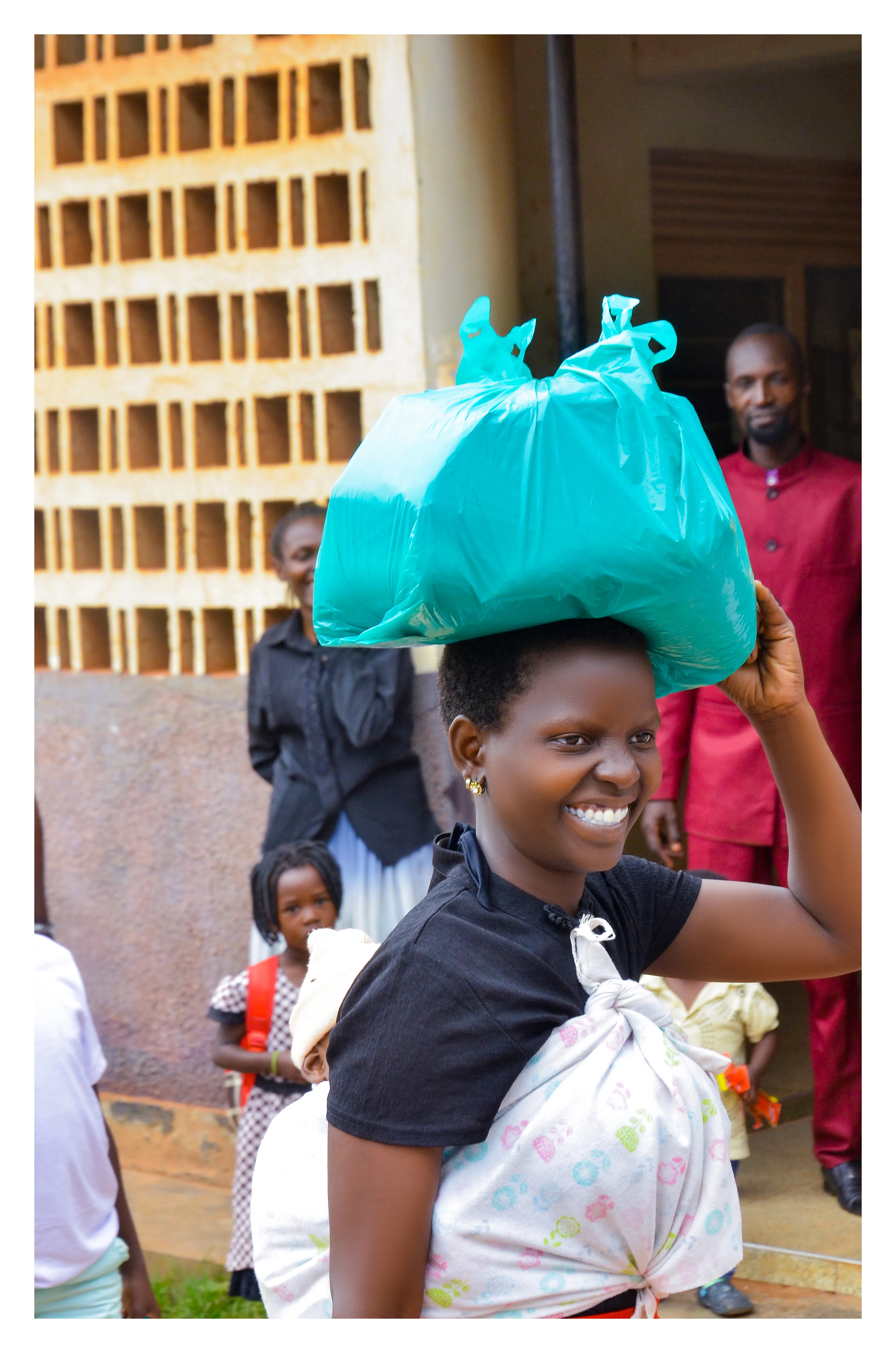A young mother carrying a parcel on her head with a baby on her back