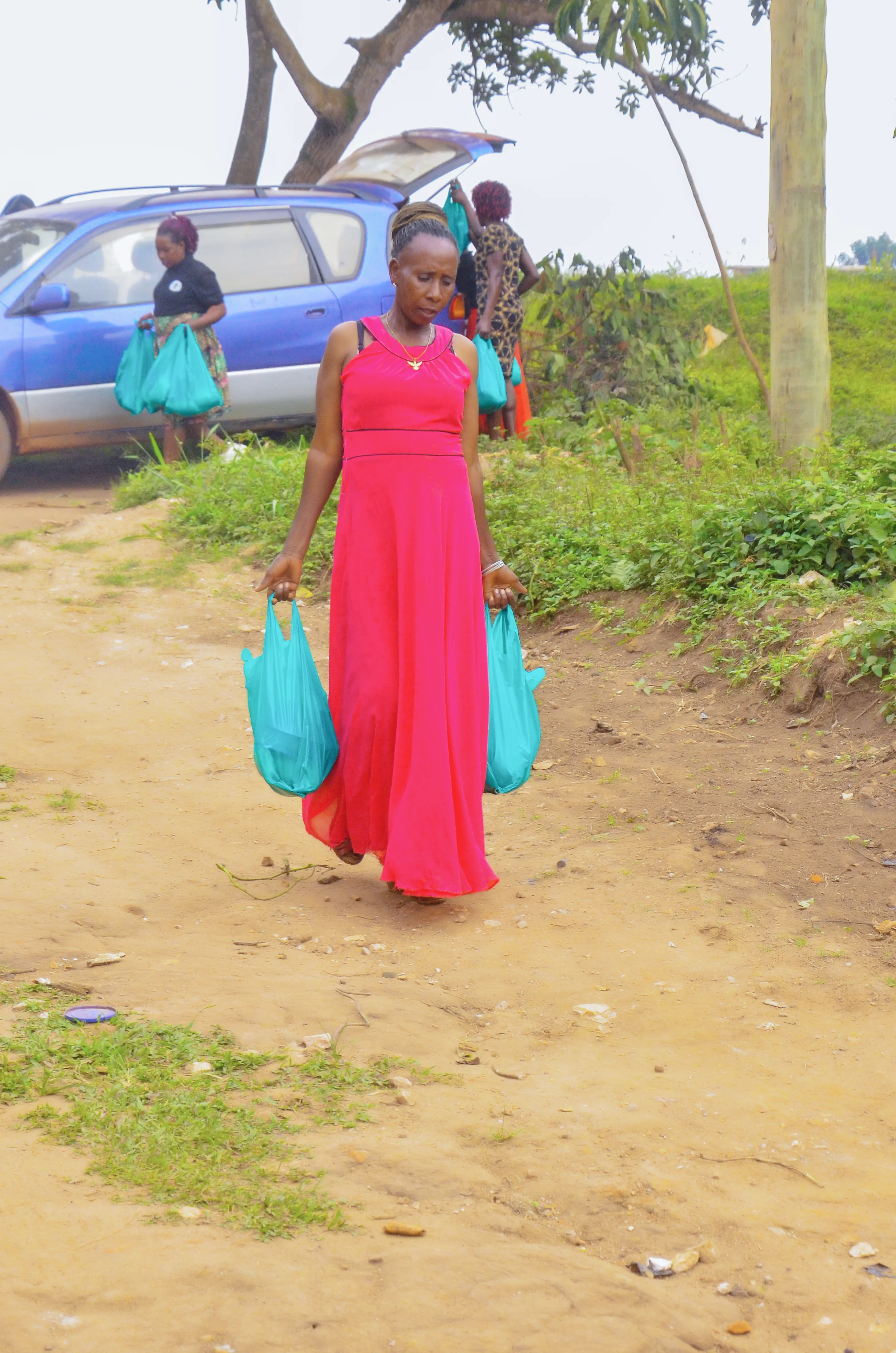 A woman carrying supply bags along a village path
